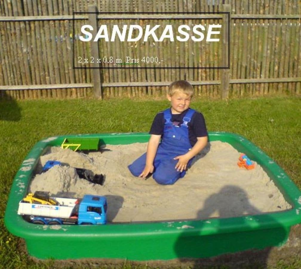 Dreng leger i grøn sandkasse med legetøj